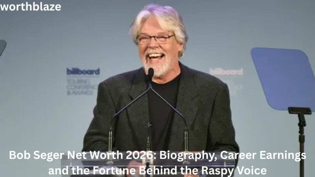 Bob Seger smiling while speaking at an event podium, highlighting the topic of Bob Seger Net Worth 2026 and his successful music career.