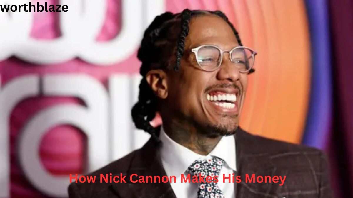 Nick Cannon smiling at a public event while wearing glasses and a suit, showcasing his successful entertainment career and Nick Cannon Net Worth.