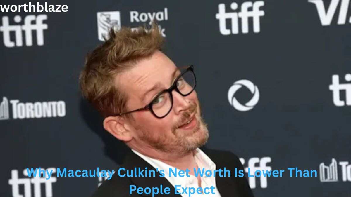 Macaulay Culkin at a public event wearing glasses and a black suit, featured in an article discussing Macaulay Culkin Net Worth and his career earnings.