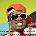 Nick Cannon smiling at a public event while wearing an orange cap, white sunglasses, and headphones, featured in an article about Nick Cannon Net Worth and his entertainment career success.