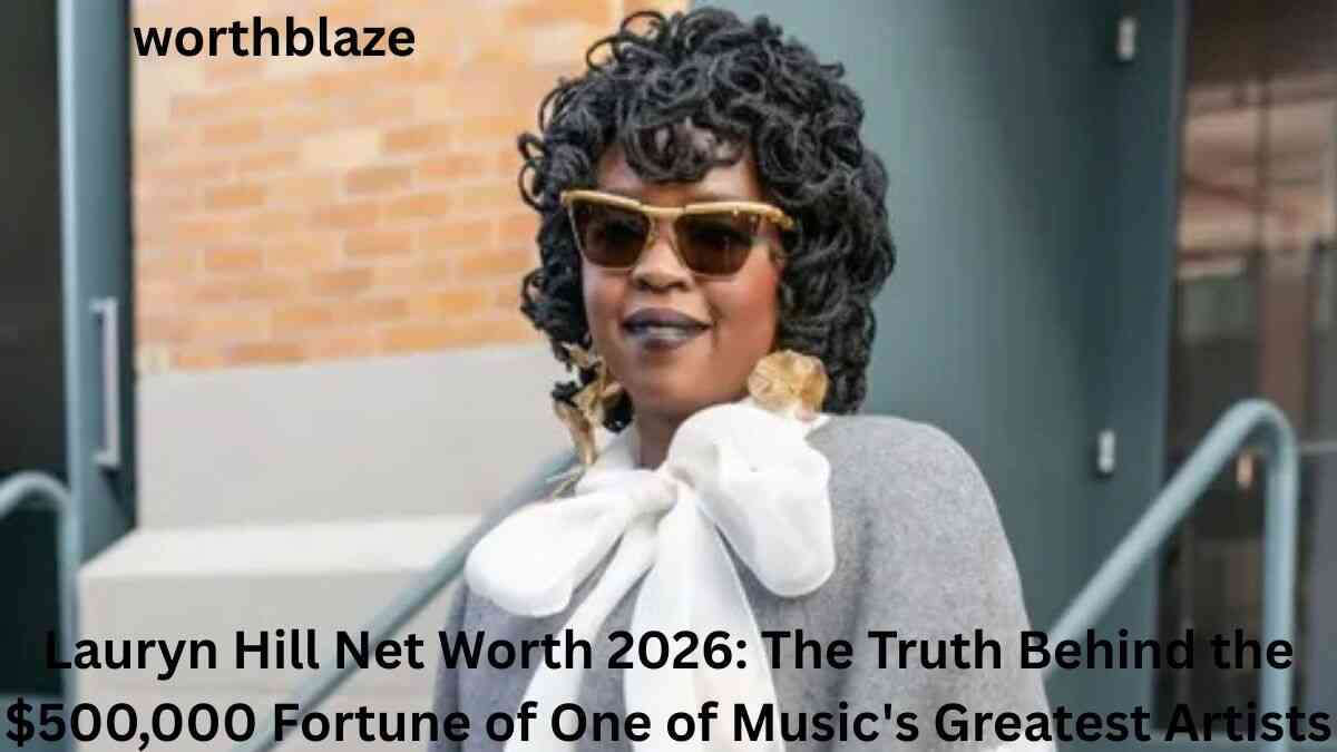 Lauryn Hill wearing sunglasses and a large white bow blouse, featured in an article about Lauryn Hill Net Worth 2026 and her estimated $500,000 fortune.